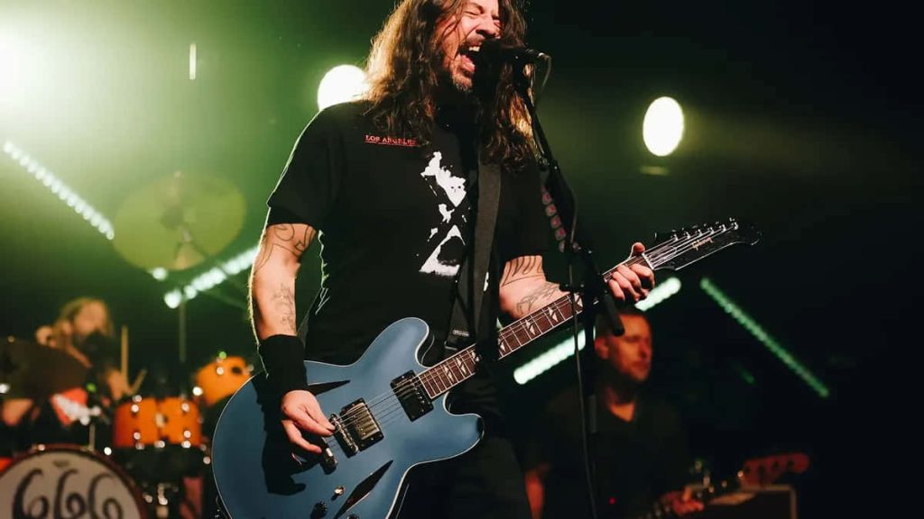 Dave Grohl performing live with blue guitar under green lights Foo Fighters concert wallpaper