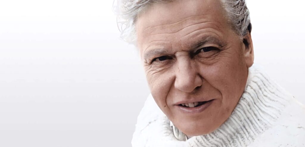 David Attenborough portrait wallpaper calm introspective mood white sweater minimalist background
