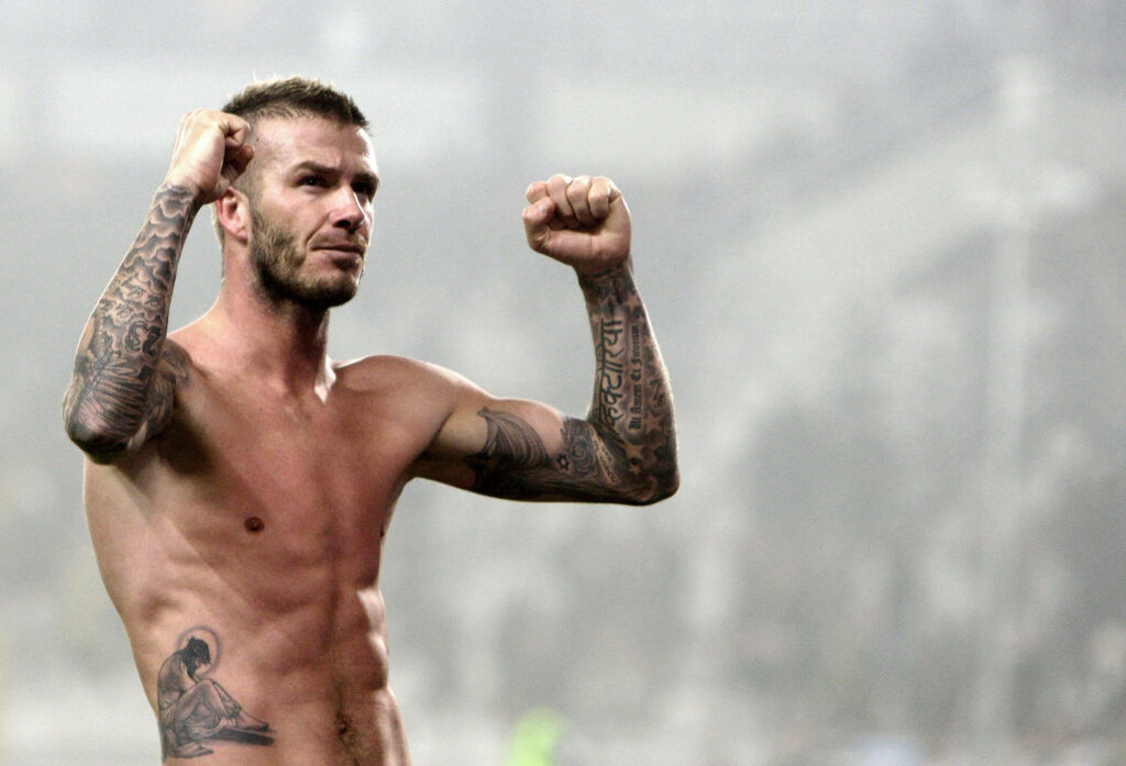 Dynamic David Beckham Wallpaper: Confident Pose & Tattoos in Stadium