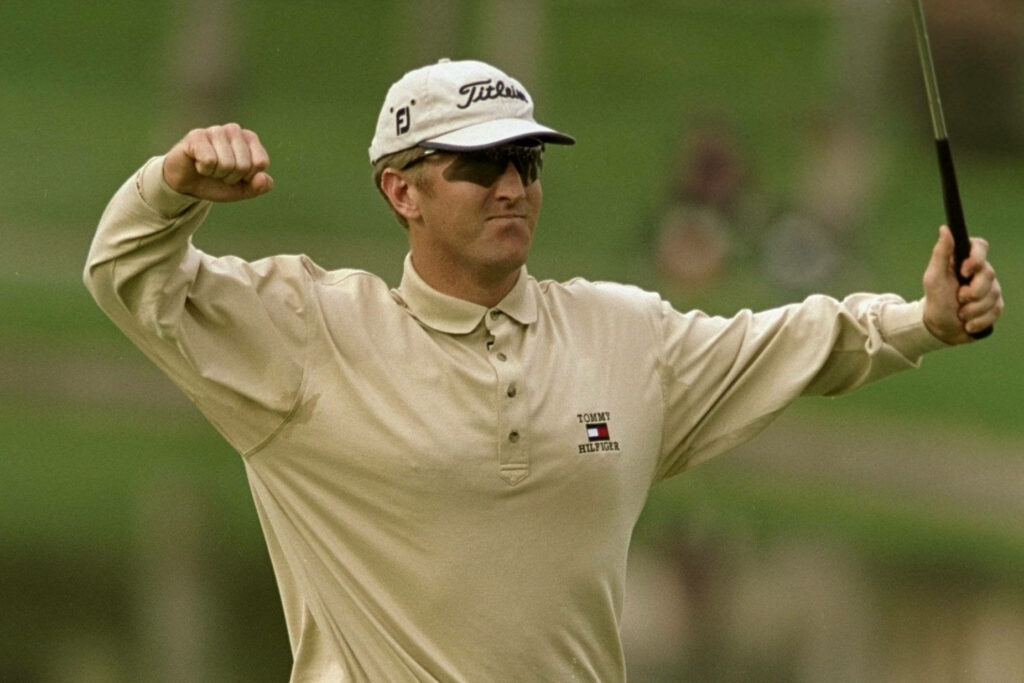 David Duval fist pumps celebrating on green golf course wearing beige shirt sunglasses and cap Wallpaper