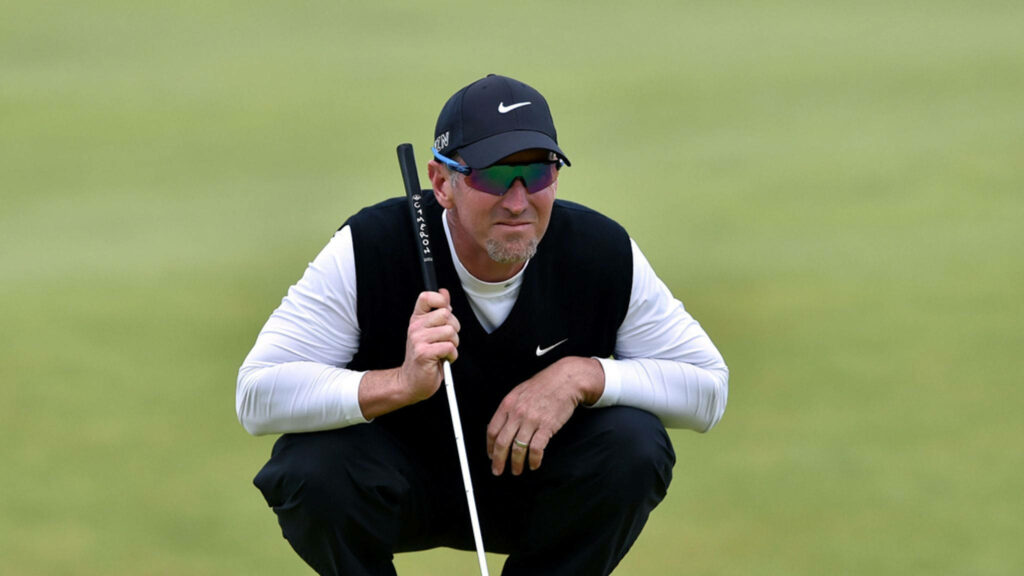 David Duval focused on golf course wearing black vest white sleeves and signature cap serene background Wallpaper