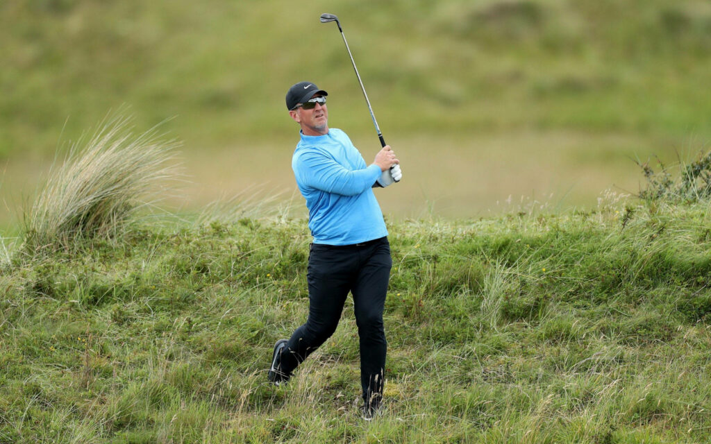 David Duval focused on golf ball after swing in light blue pullover on green golf course background Wallpaper