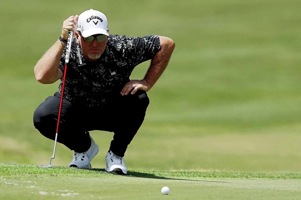 David Duval focused lining up putt on sunlit golf course wearing black shirt white cap sunglasses Wallpaper