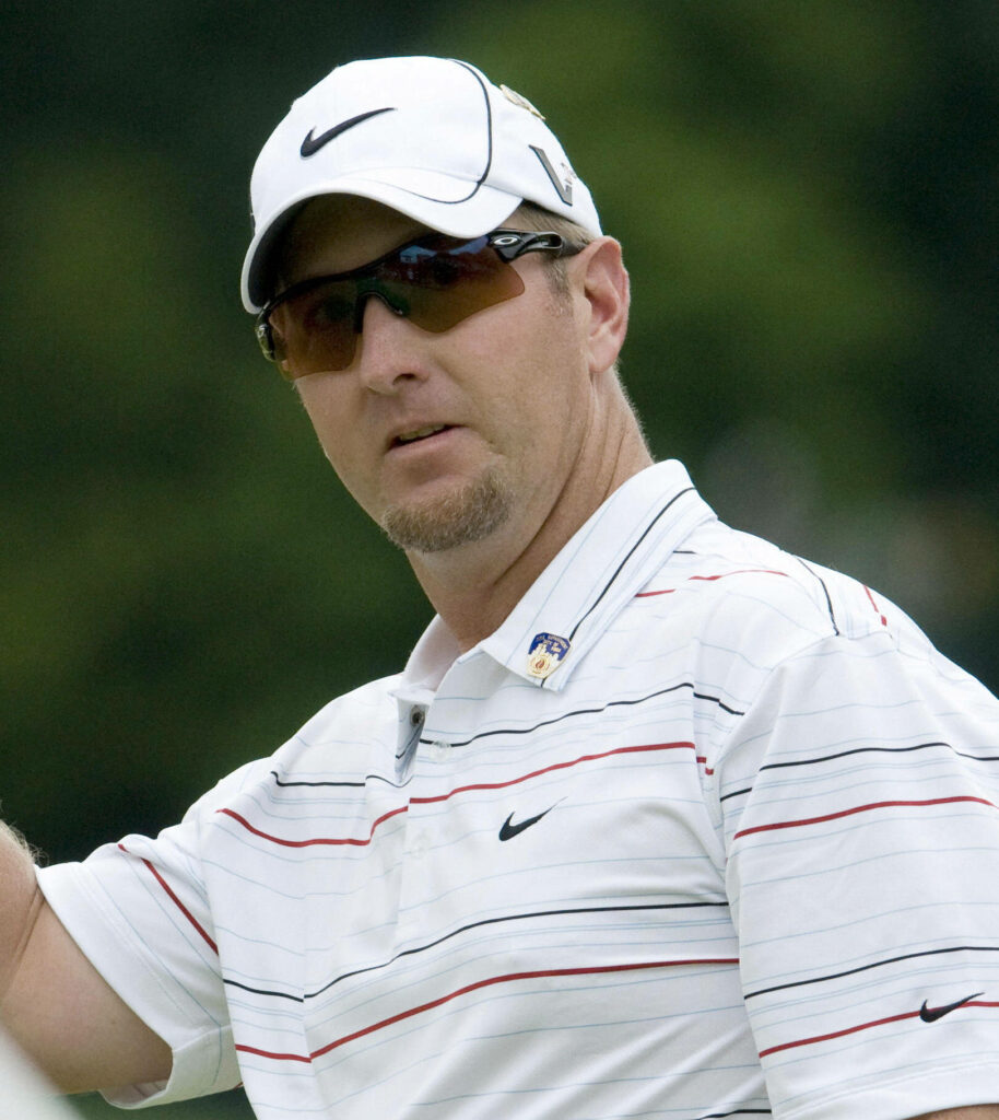 David Duval focused on golf course wearing brown sunglasses white Nike cap striped polo shirt outdoors Wallpaper
