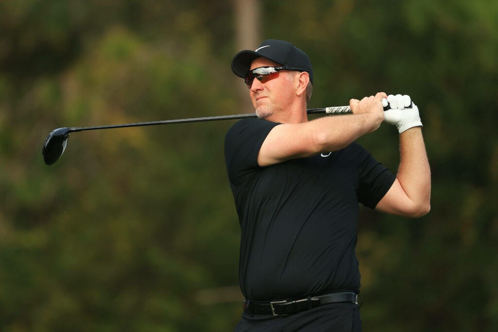 David Duval swinging golf club in black outfit cap sunglasses on green course professional golf action Wallpaper