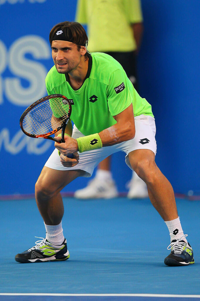 David Ferrer in bright green shirt ready stance on vibrant blue hard court showcasing focus Wallpaper
