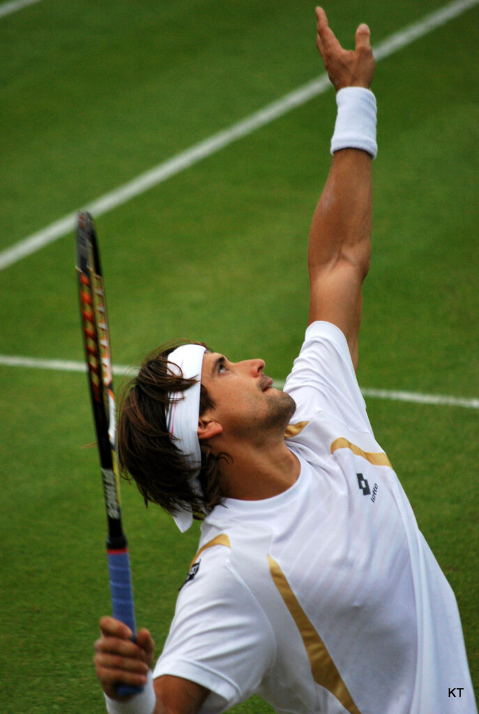 David Ferrer mid serve on grass court focused athletic pose white headband professional tennis action Wallpaper