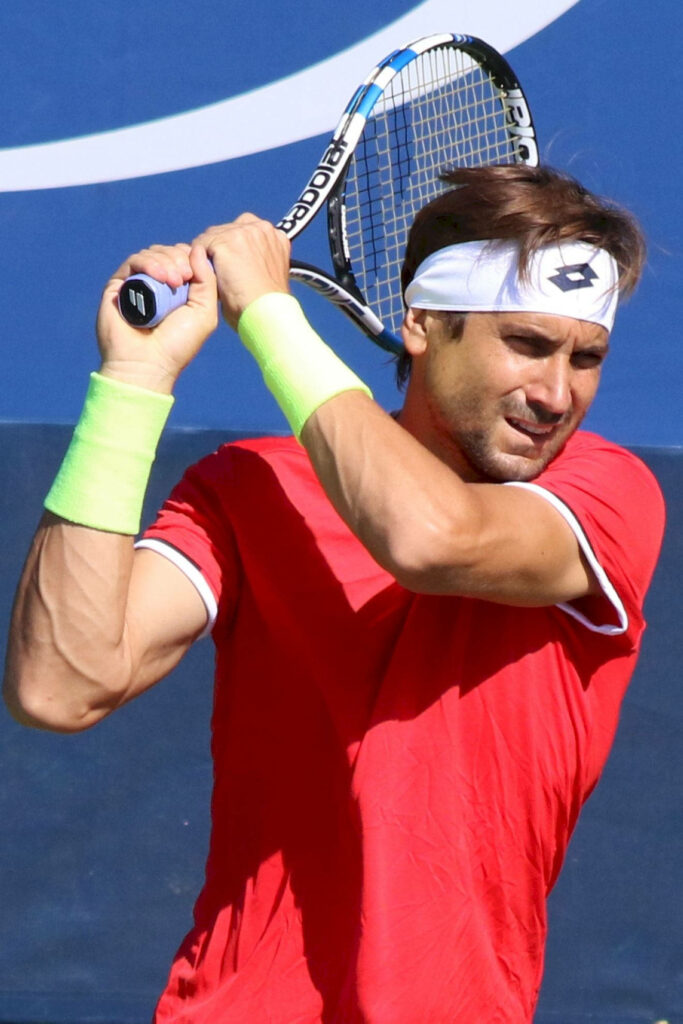 David Ferrer in red shirt neon green wristbands holding tennis racket on court high focus action Wallpaper