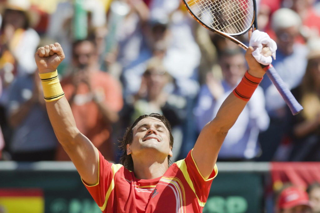 David Ferrer celebrates tennis victory wearing red and yellow outfit with cheering crowd background Wallpaper