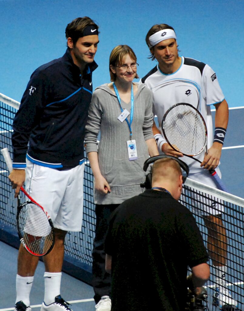 David Ferrer and Roger Federer with fan on indoor tennis court holding racquets in sportswear Wallpaper