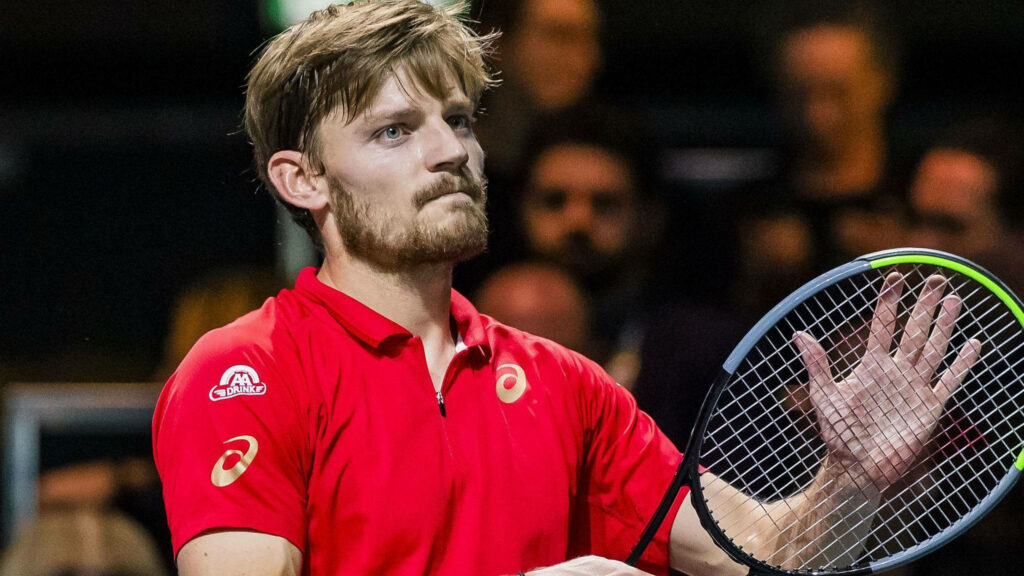 David Goffin focused on tennis court wearing red shirt holding racket during intense match moment Wallpaper