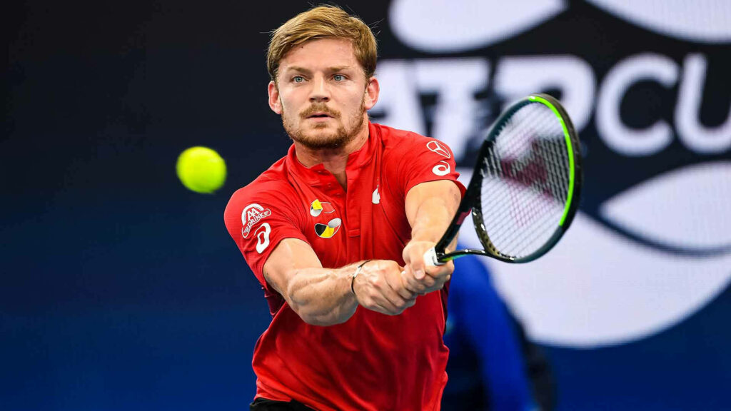 David Goffin in red shirt hitting tennis ball mid-air with intense focus dynamic wallpaper