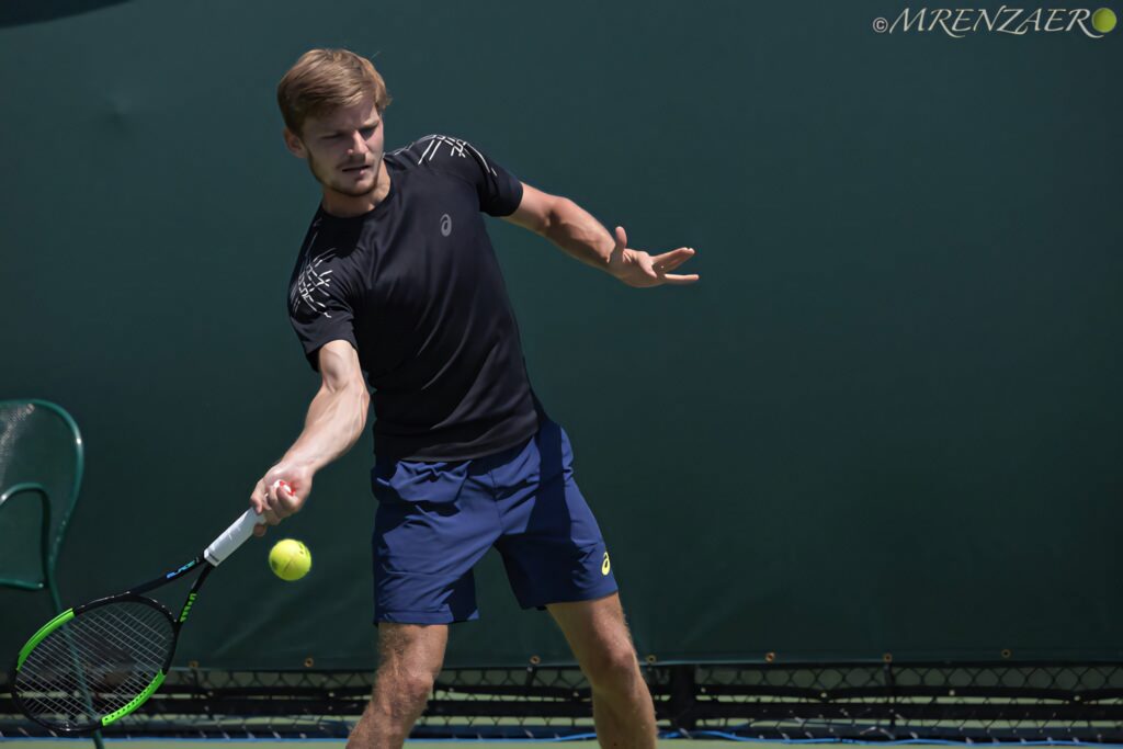 David Goffin tennis pro focused returning shot wearing blue shorts and black sportswear on court Wallpaper