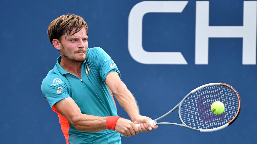 David Goffin two-handed backhand tennis shot on deep blue court in vibrant teal orange gear Wallpaper