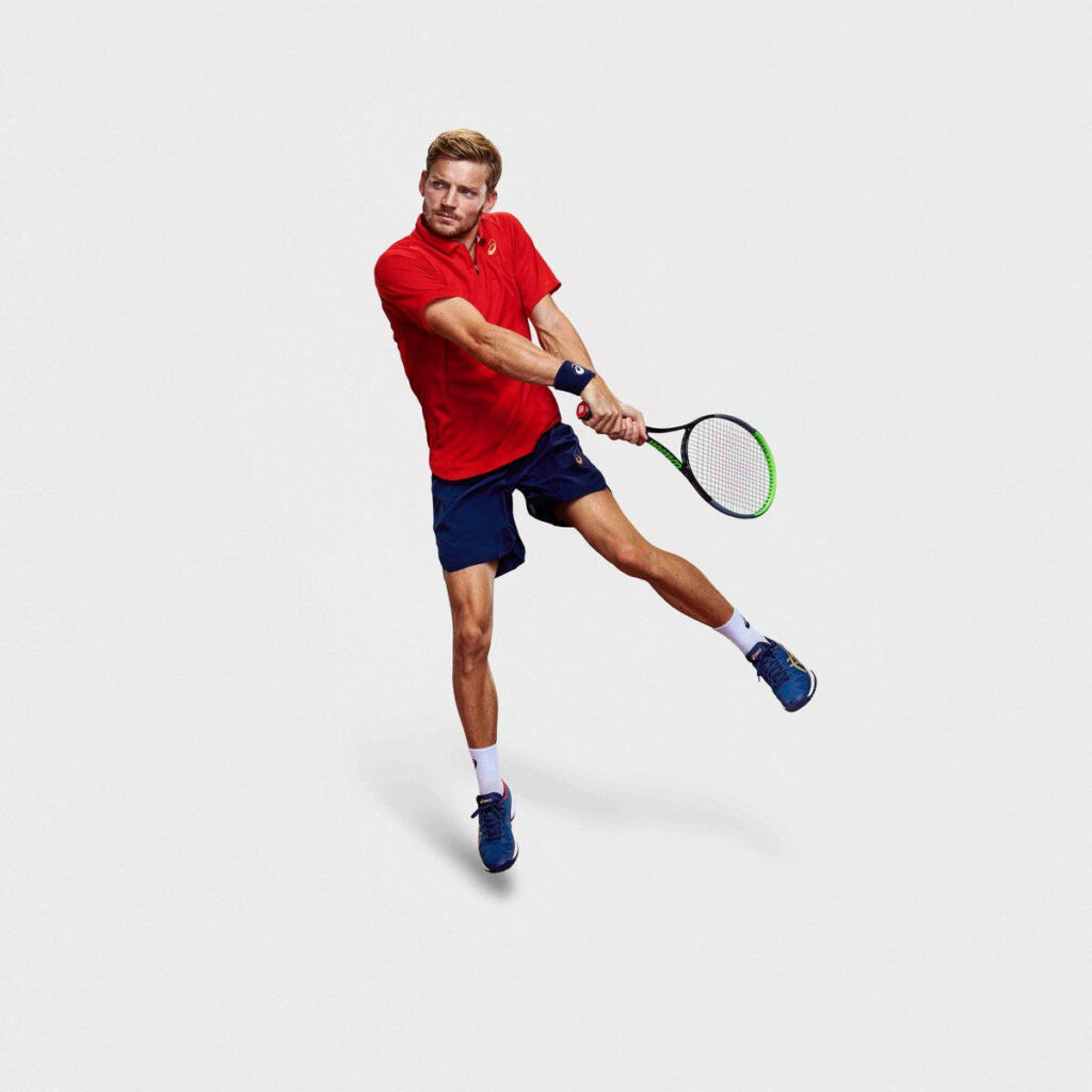 David Goffin tennis player in red shirt mid-action on white background vibrant sports wallpaper