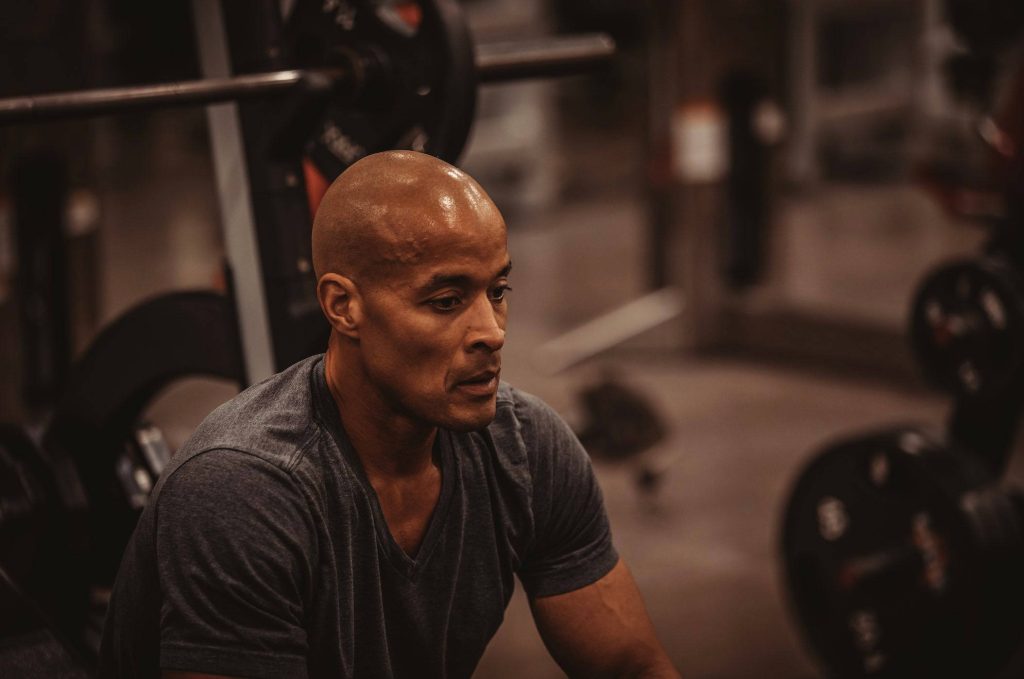 David Goggins intense focused gym portrait wallpaper with moody dark background for discipline