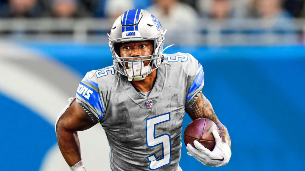 David Montgomery Detroit Lions running back charging forward in full gear against stadium backdrop Wallpaper