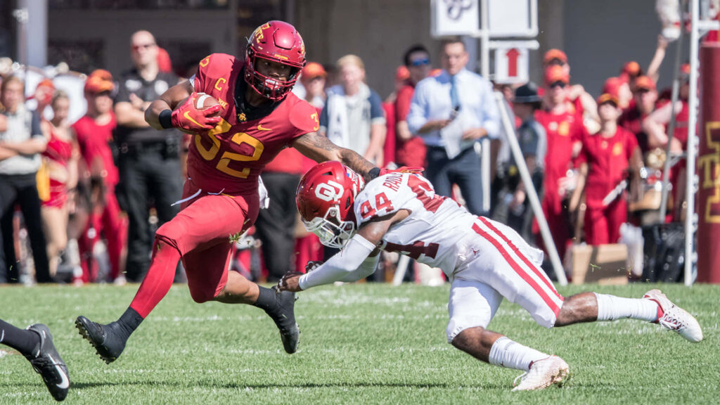 David Montgomery sprinting in Iowa State Cyclones crimson gold uniform evading tackle college football Wallpaper