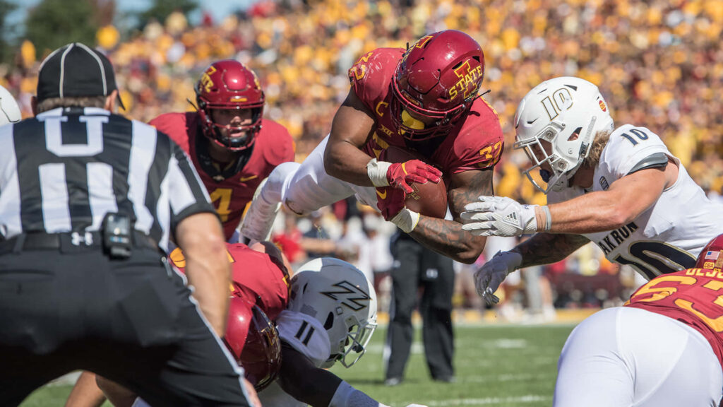 David Montgomery diving in Iowa State football uniform during intense college game with fans Wallpaper