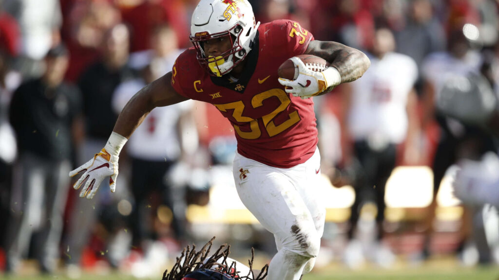 David Montgomery running with football in red and gold uniform showcasing speed and power Wallpaper