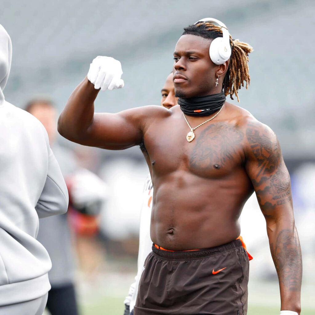 David Njoku training showing muscular physique athleticism tattoos wireless headphones stadium background Wallpaper