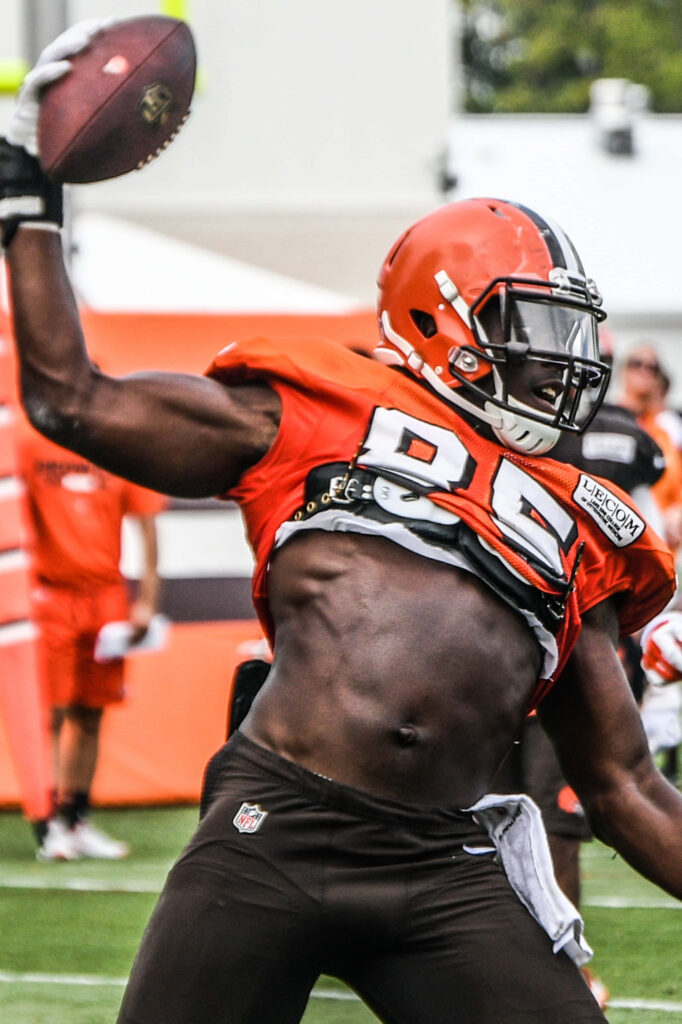 David Njoku catching football mid-action in Cleveland Browns uniform on training field background Wallpaper