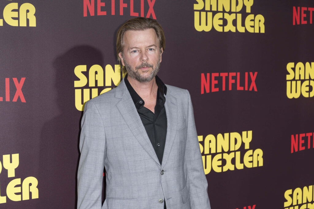 David Spade in light gray suit at Sandy Wexler Netflix premiere with warm event lighting Wallpaper