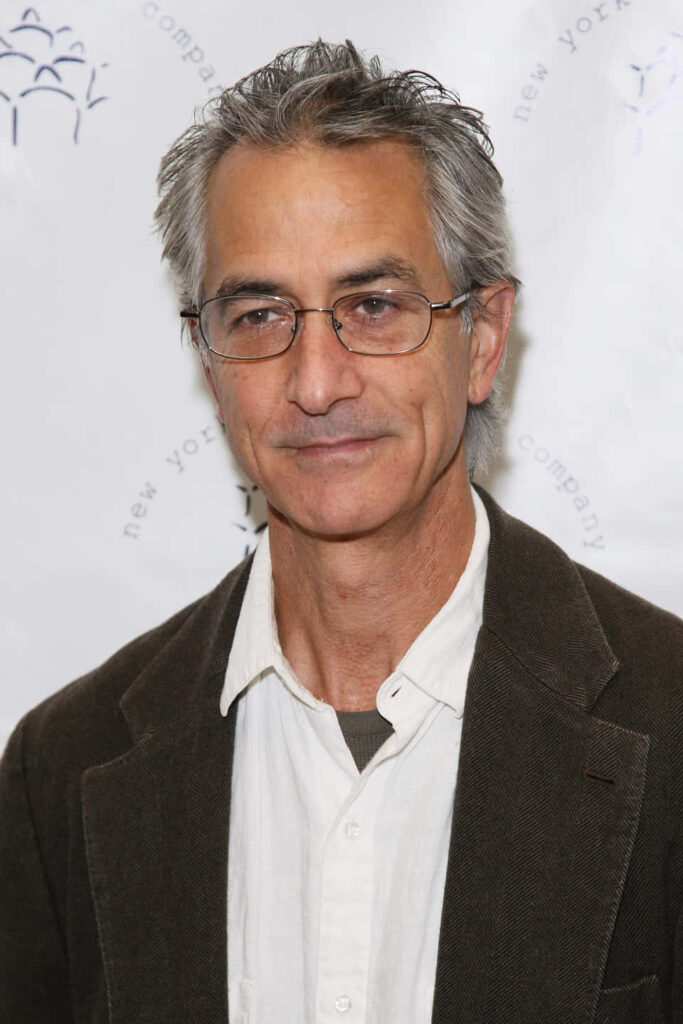 David Strathairn in brown jacket and white shirt against soft white background classic style wallpaper