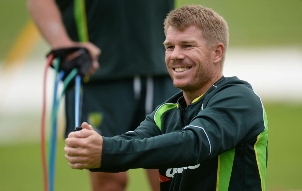 David Warner clapping in Australian cricket green sportswear during outdoor training session Wallpaper