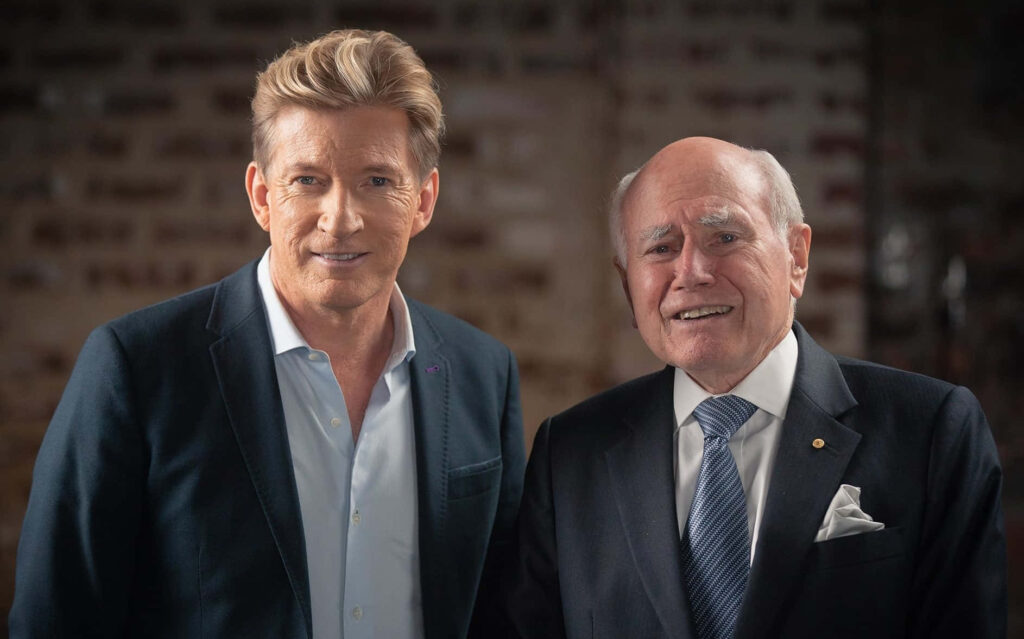 Australian actor David Wenham with former Prime Minister John Howard in formal suits near brick wall Wallpaper