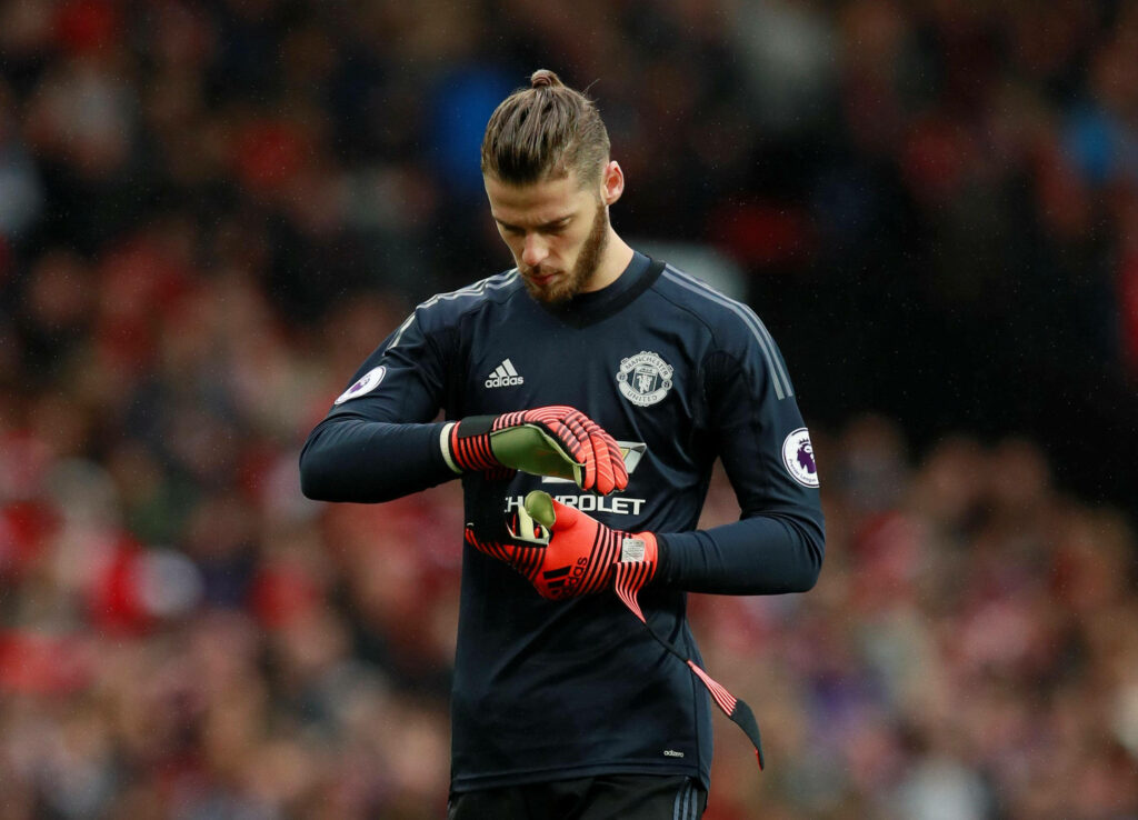 David de Gea focused adjusting gloves in dark Manchester United goalkeeper kit stadium background Wallpaper