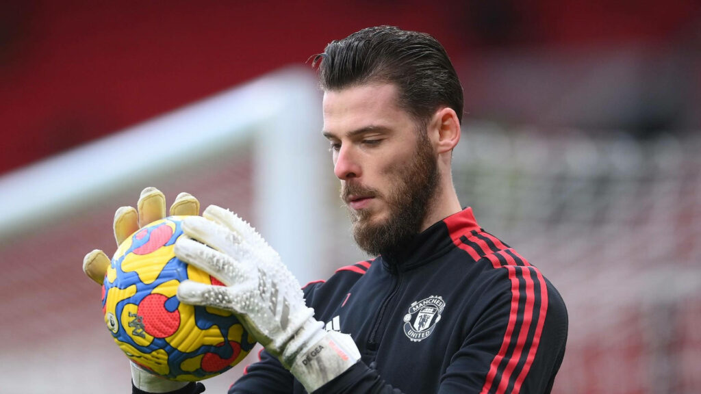 David de Gea focused on colorful football wearing Manchester United training kit in stadium background Wallpaper