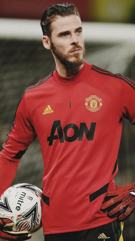 David de Gea confident in red Manchester United training kit with blurred stadium background wallpaper