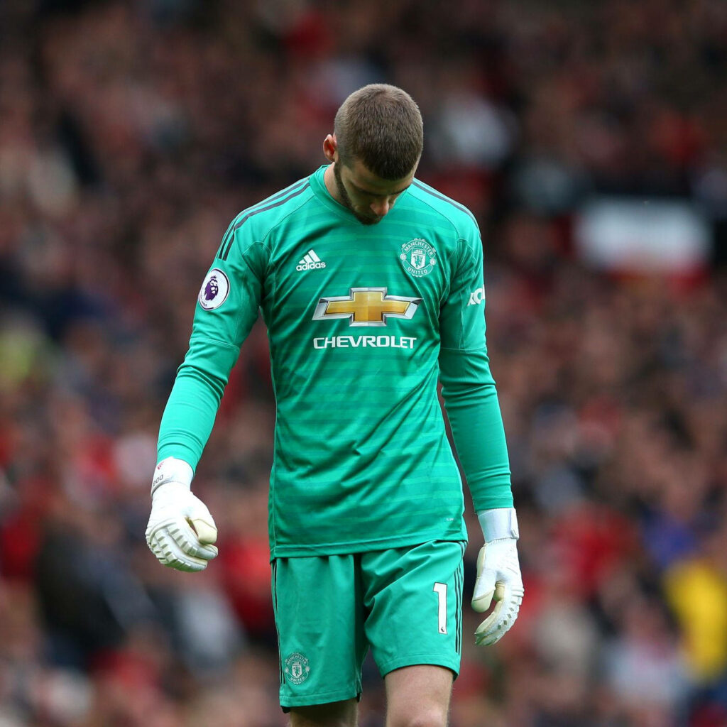 David de Gea in green Manchester United goalkeeper kit reflecting on pitch with blurred crowd background Wallpaper