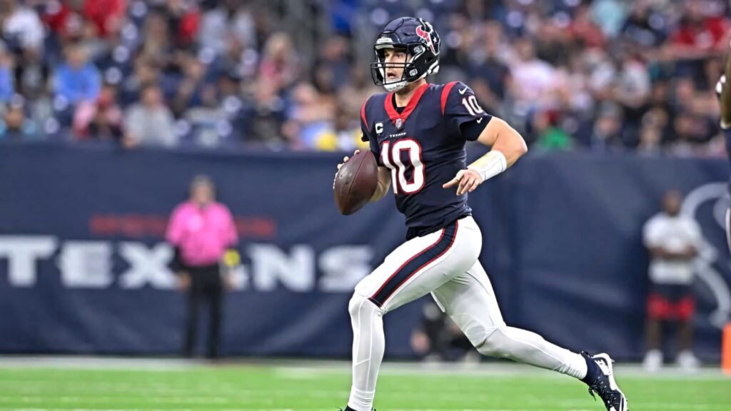 Davis Mills Houston Texans quarterback sprinting in dark blue red uniform on vibrant football field Wallpaper