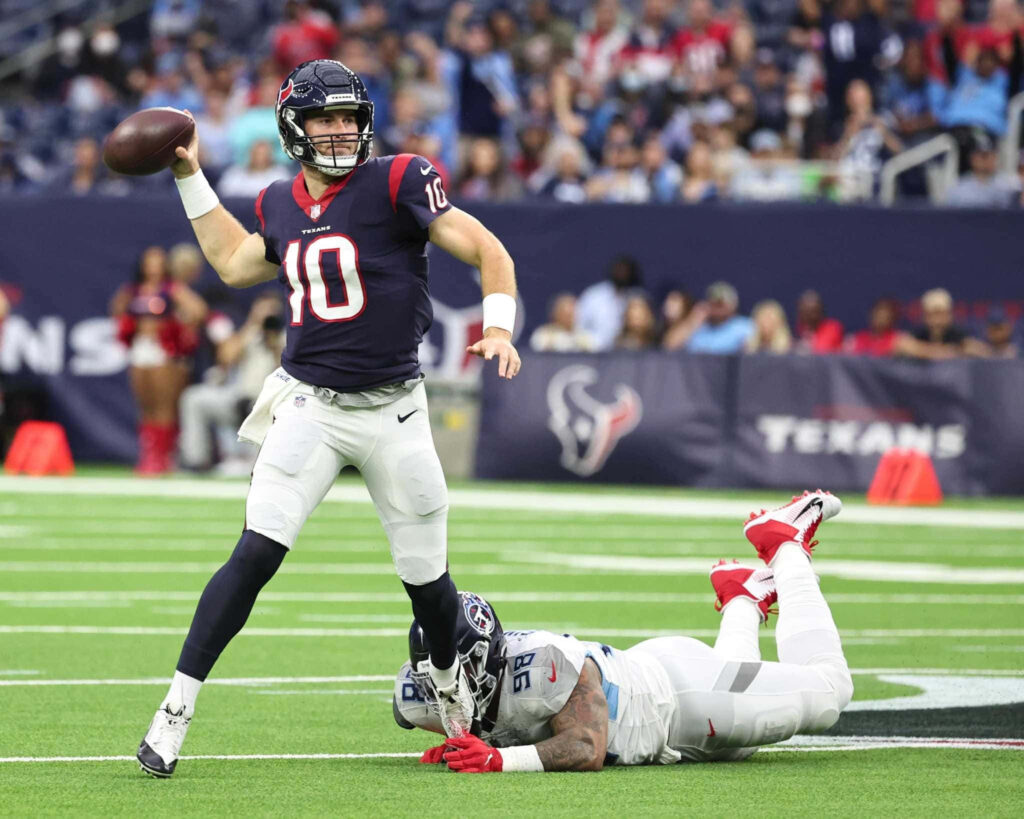 Houston Texans quarterback Davis Mills dodging tackle mid-action showing focus and agility Wallpaper