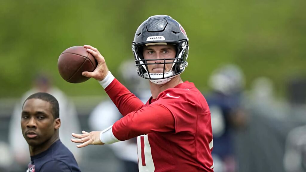 Davis Mills in red jersey and helmet throws football showing focus during practice session outdoors Wallpaper