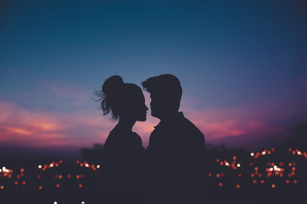 Romantic couple silhouette at twilight purple sky with glowing city lights bokeh wallpaper background