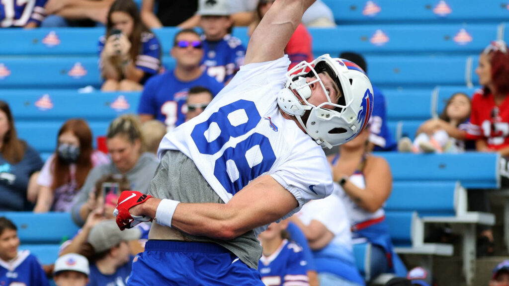 Dawson Knox airborne catching football in stadium with vibrant team colors and cheering fans Wallpaper