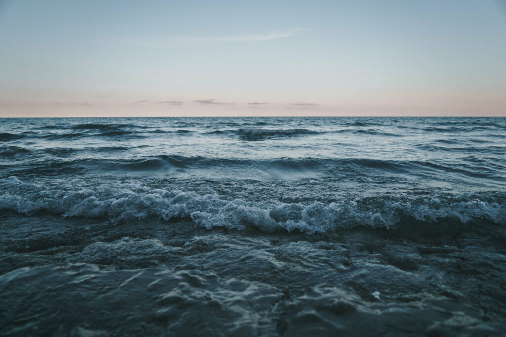 Captivating Coastal Majesty: HD Wallpaper of Sunlit Ocean Waves Illuminating a Stunning Sea Background