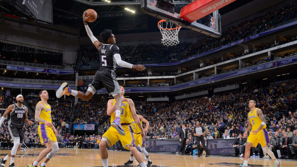 DeAaron Fox soaring for a poster dunk over Lakers in packed arena with vibrant team colors Wallpaper