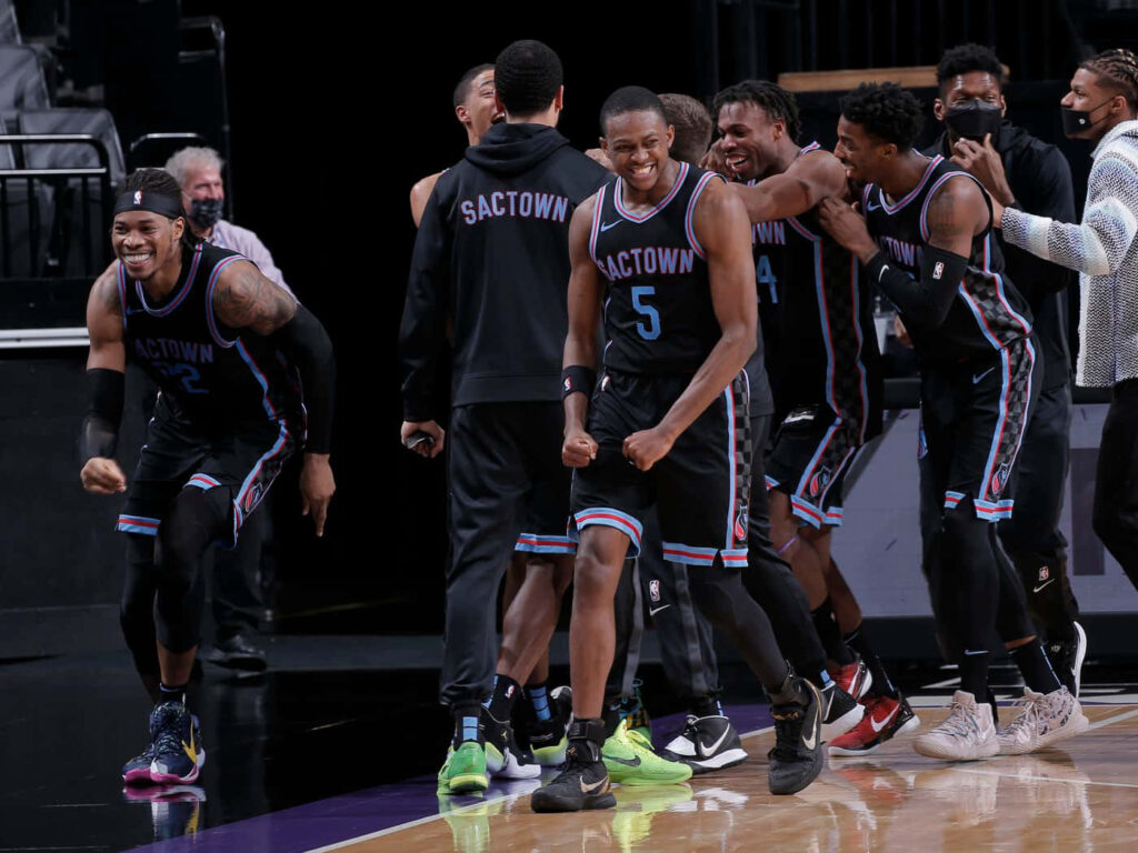 DeAaron Fox and Sacramento Kings teammates in black uniforms celebrating on dynamic NBA court Wallpaper