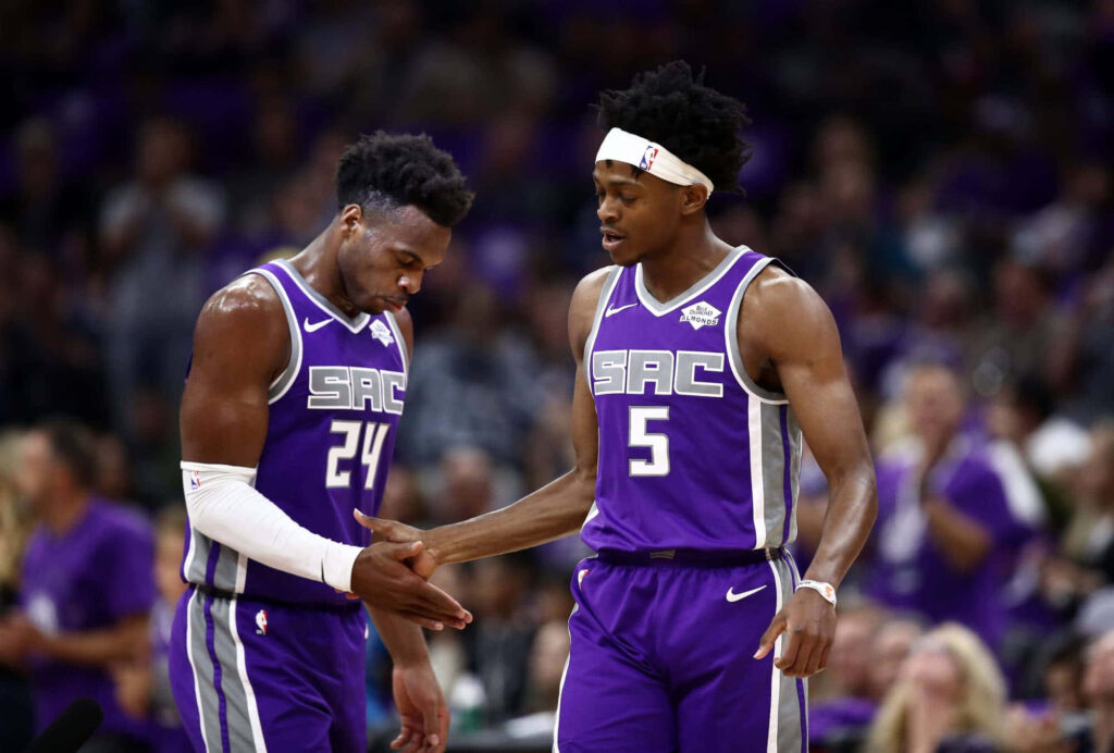 De Aaron Fox and Buddy Hield Sacramento Kings handshake in purple uniforms NBA game teamwork Wallpaper