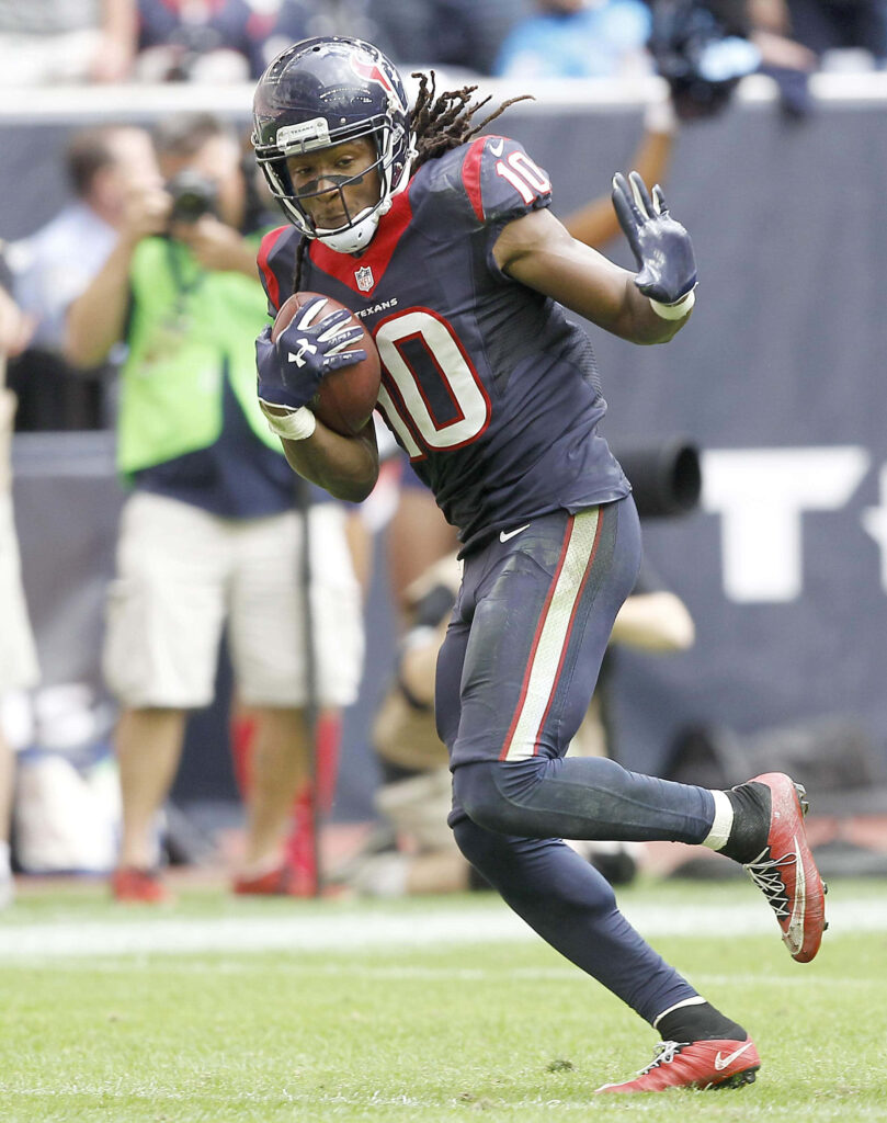 DeAndre Hopkins running with football in Houston Texans uniform on vibrant green field action shot Wallpaper