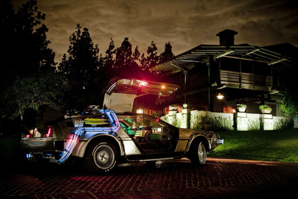 DeLorean Back to the Future parked outside house at night glowing lights futuristic design wallpaper