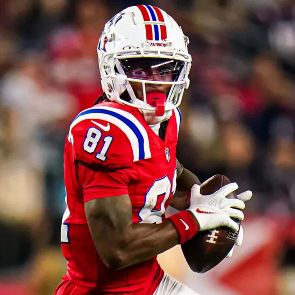 DeMario Douglas in red number 81 uniform catching football under stadium lights in action Wallpaper