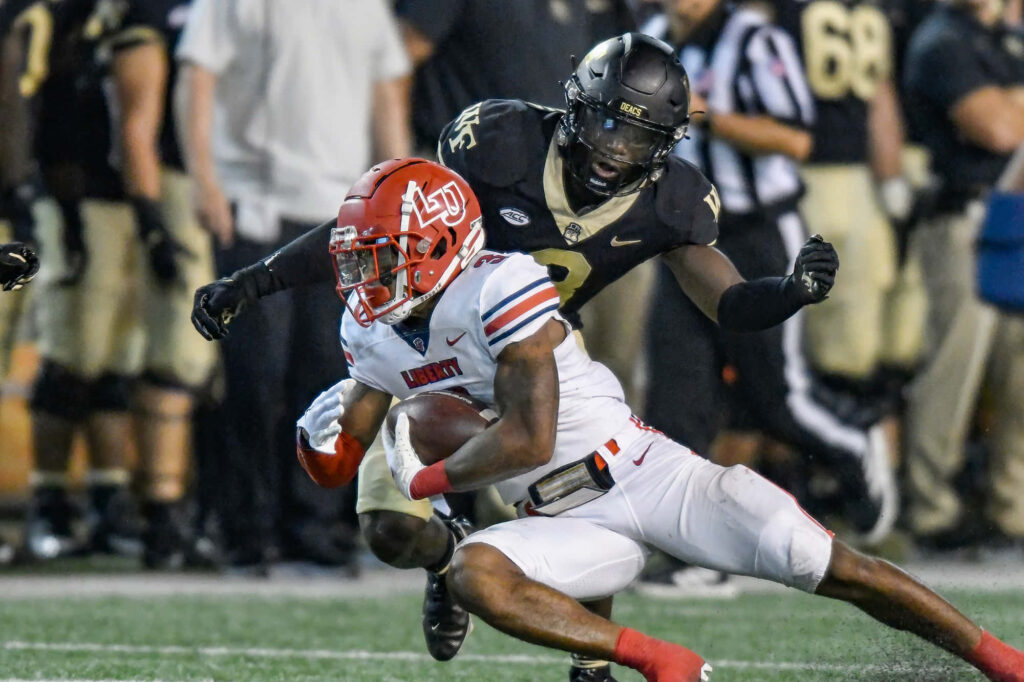 DeMario Douglas intense college football action battling defense under stadium lights wallpaper