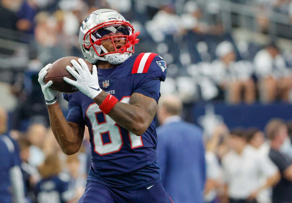 DeMario Douglas catching football in New England Patriots uniform during intense game action Wallpaper