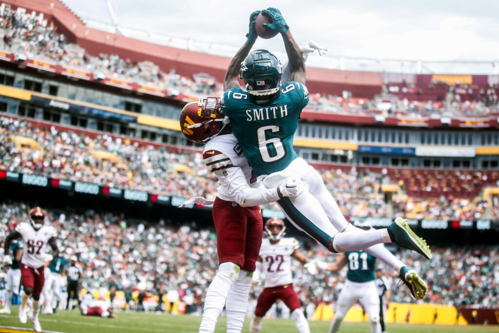 DeVonta Smith airborne making acrobatic catch in green white jersey packed stadium football wallpaper