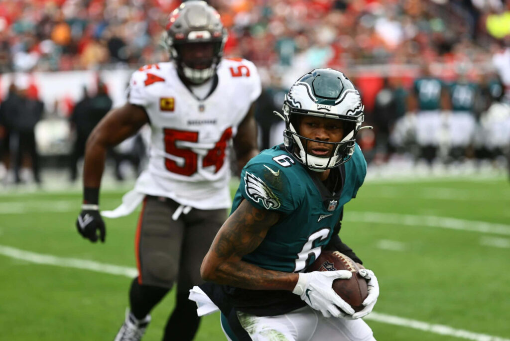 DeVonta Smith Philadelphia Eagles sprinting with football chased by defender on vibrant NFL field Wallpaper